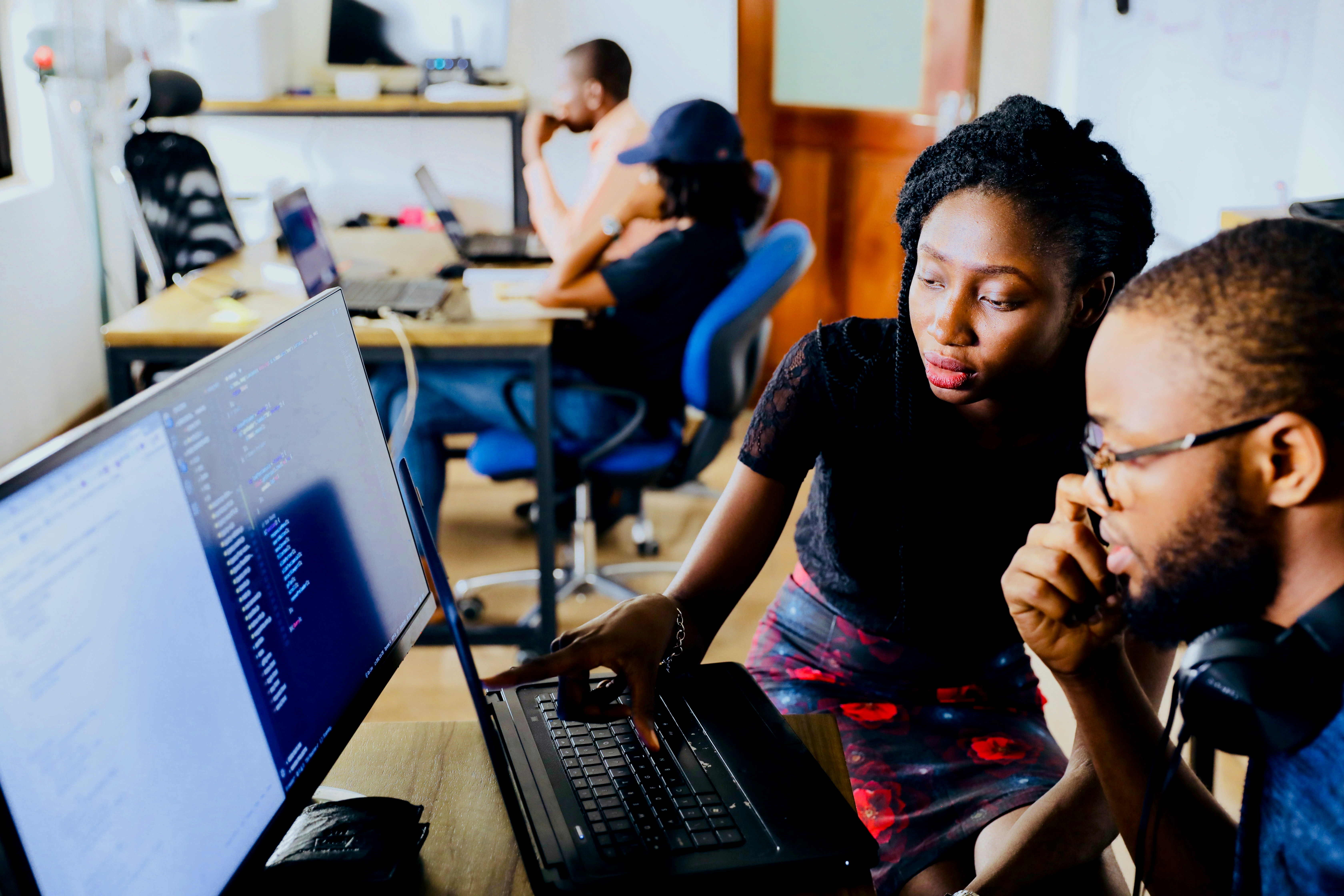 Software engineers collaborating in front of a laptop and monitors.